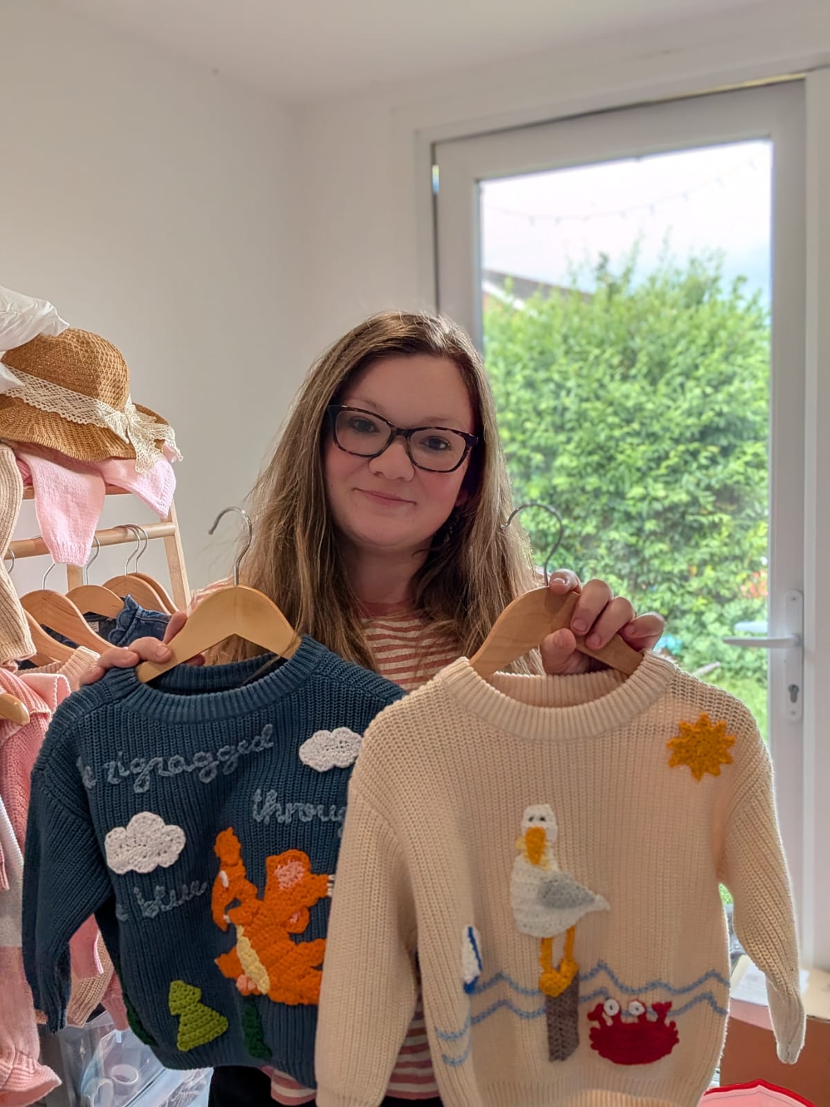 Hollie, founder of Crafty Mutt, holding two personalised children's jumpers