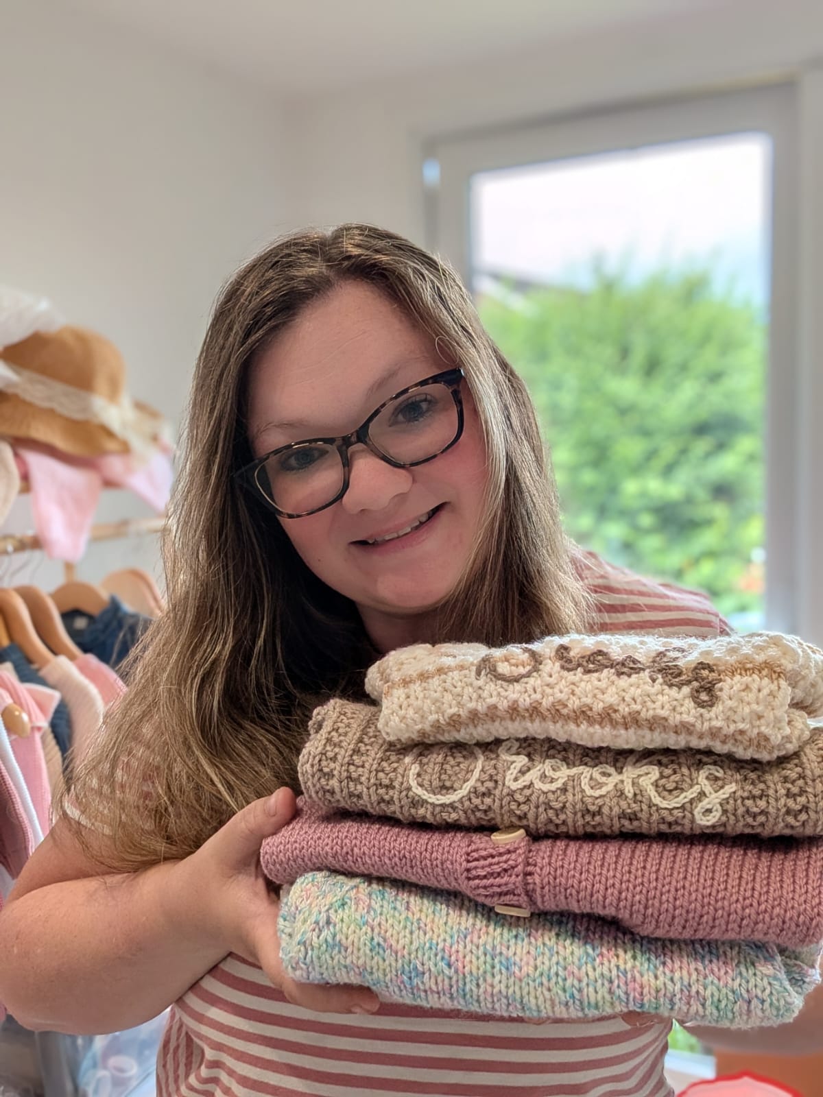 Hollie holding a stack of handmade personalised knitwear